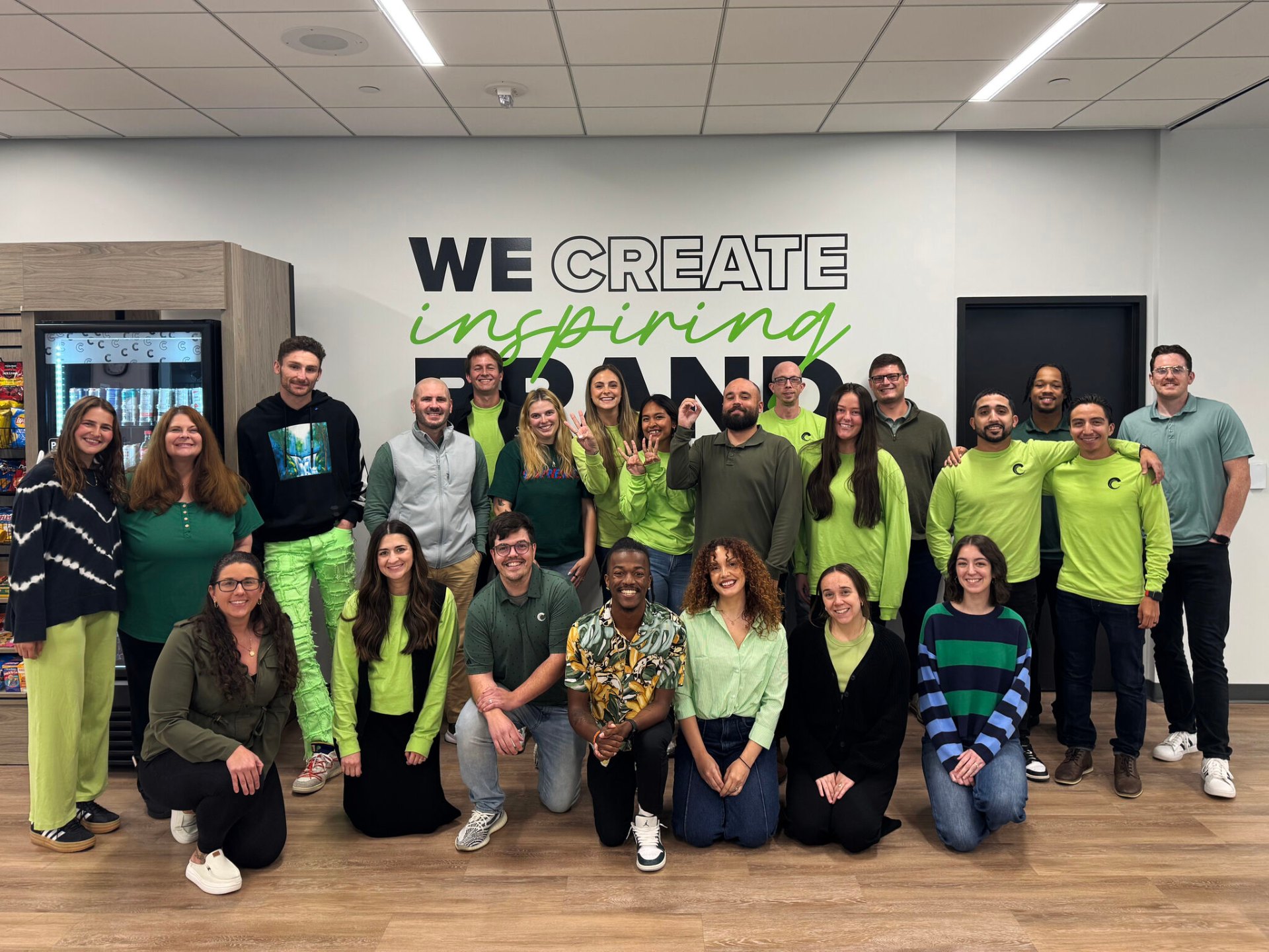 The Club Colors team gathered in front of a wall reading We create inspiring brands